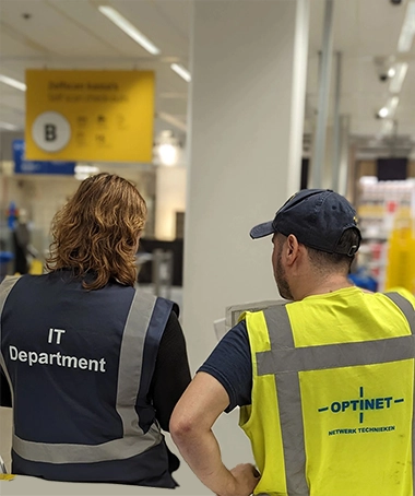 IT-medewerker en Optinet-technicus werken samen in een winkelomgeving